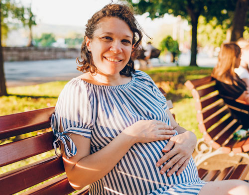 Woman pregnant andn sitting on a park bench