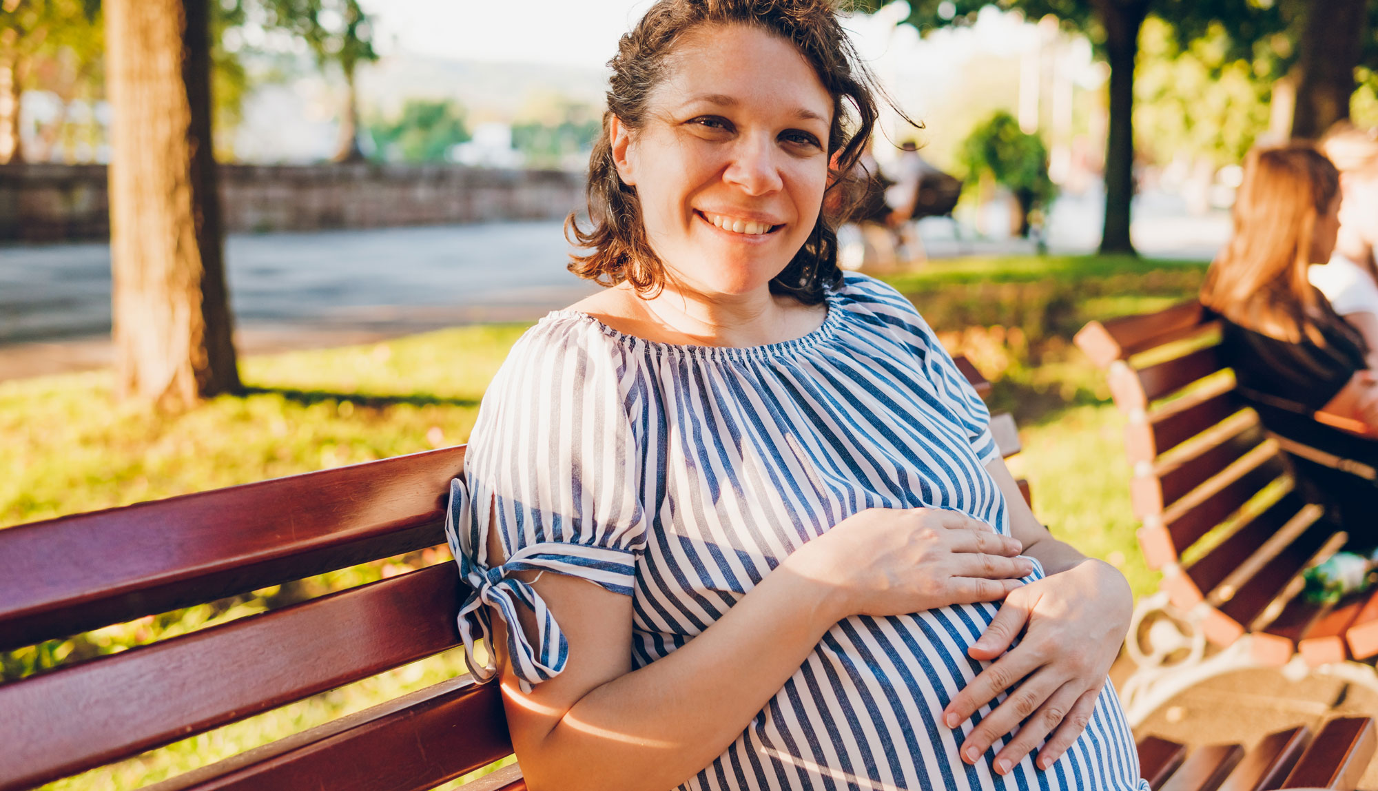 Pregnant woman sitting on a park bench